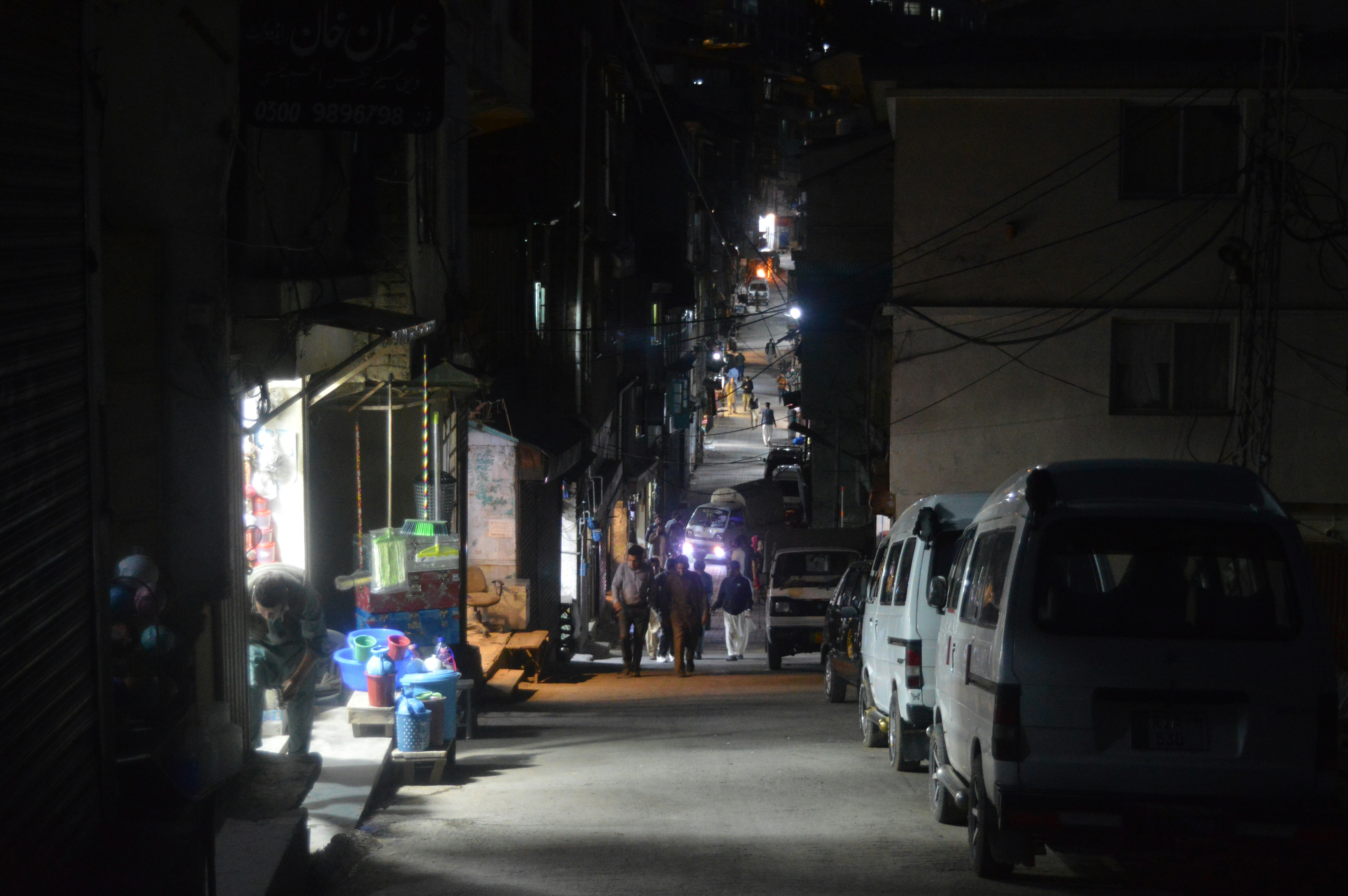 a street at night with cars parked on the side of the road