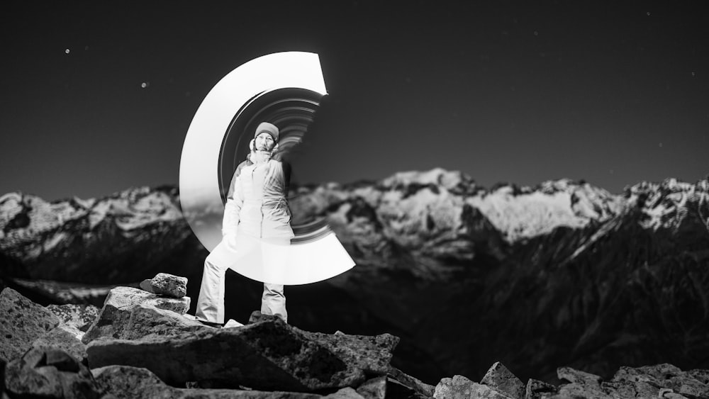 a black and white photo of a man standing on top of a mountain