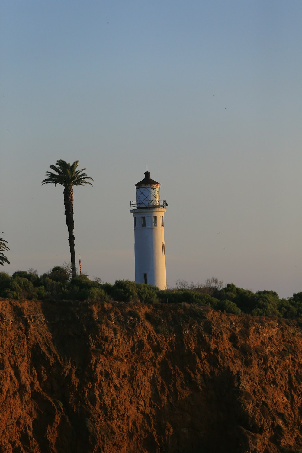 a white light house sitting on top of a hill