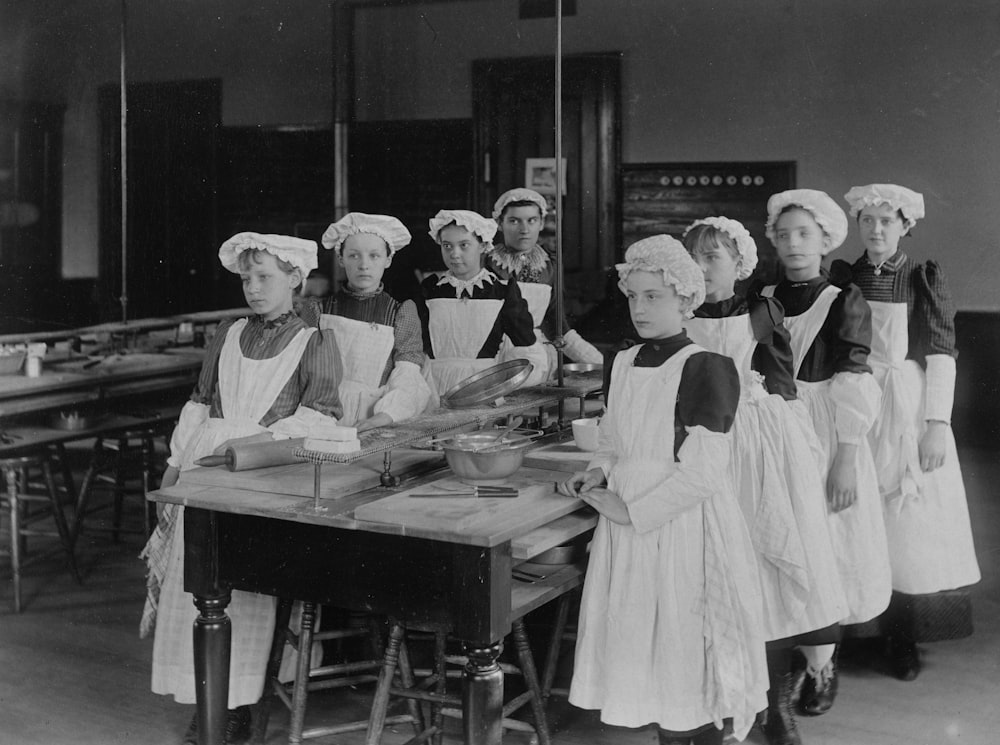 a group of women in aprons standing around a table