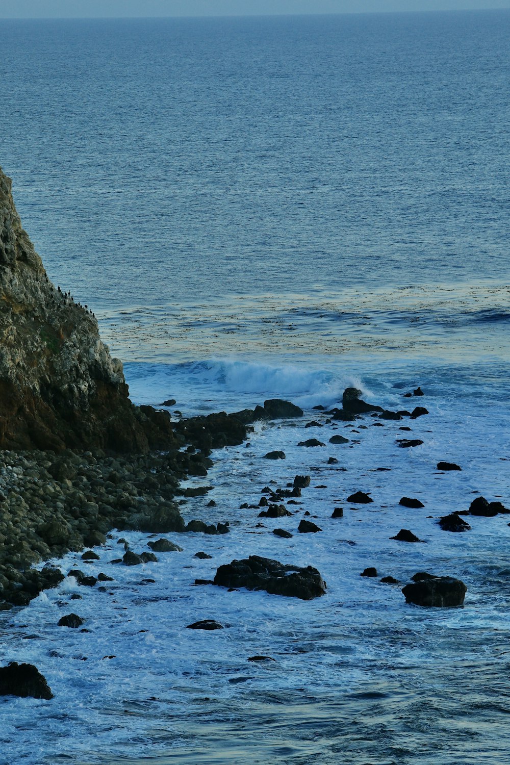 a person walking along a rocky beach next to the ocean