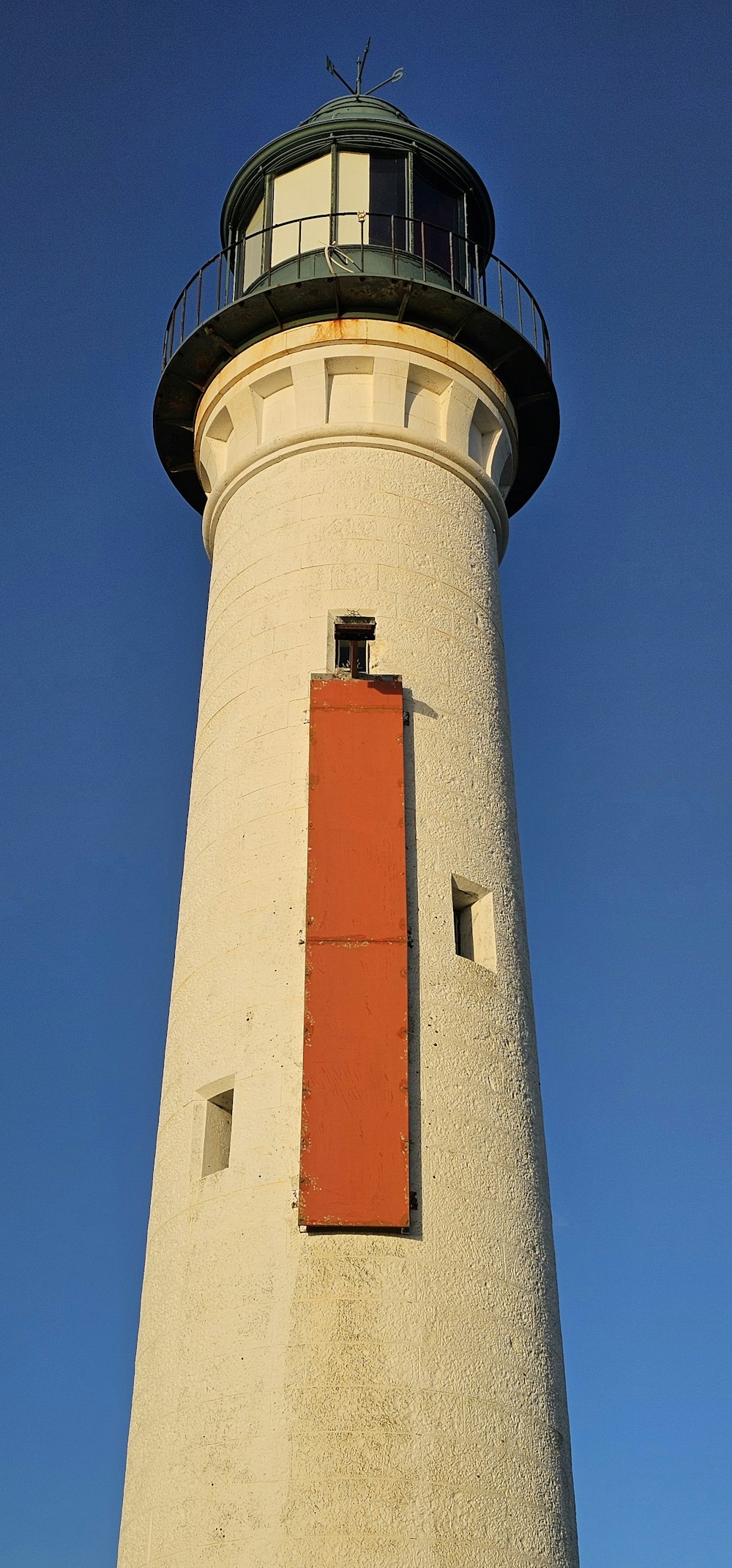 a tall white lighthouse with a red door