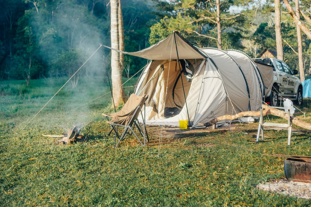 a tent is set up in the grass near a campfire