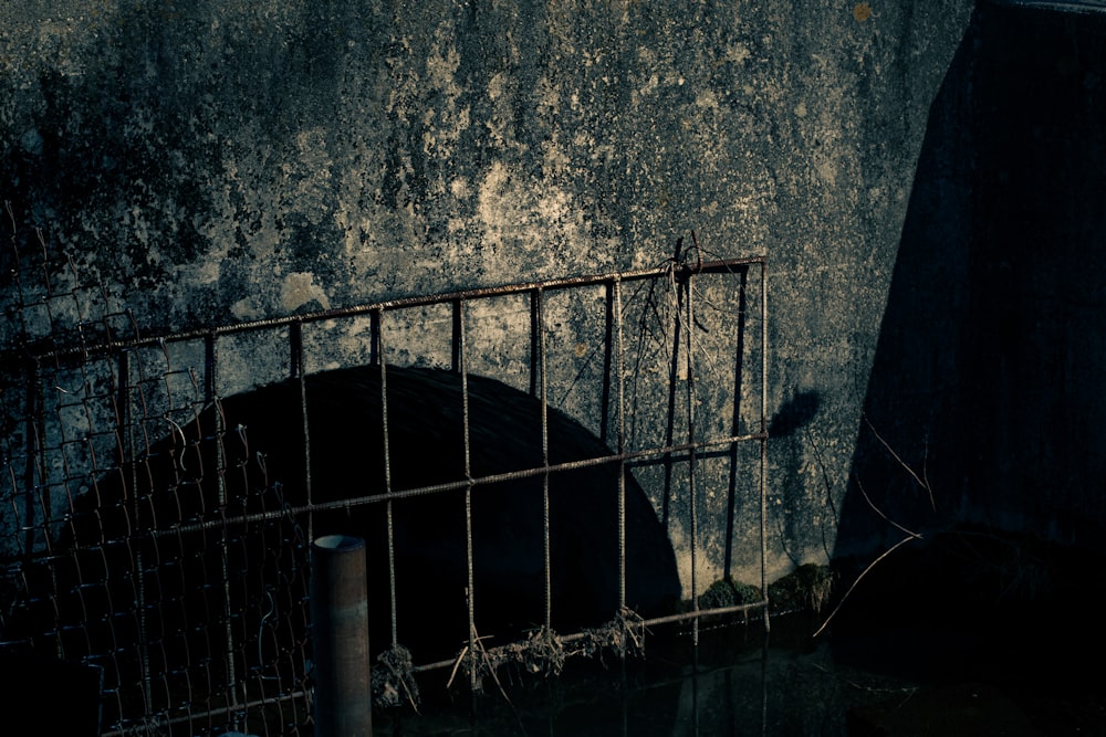 un paraguas negro sentado en una jaula junto a una pared