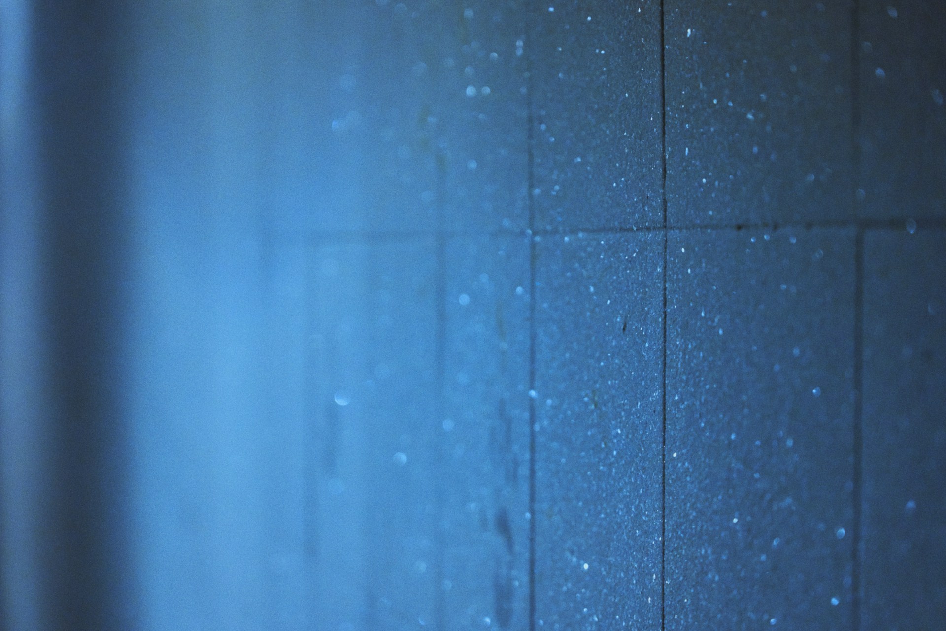 a blue tiled wall with water droplets on it