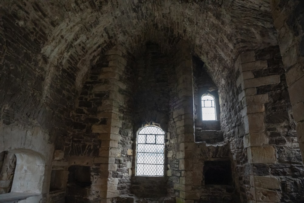 una habitación de piedra con dos ventanas y un aseo