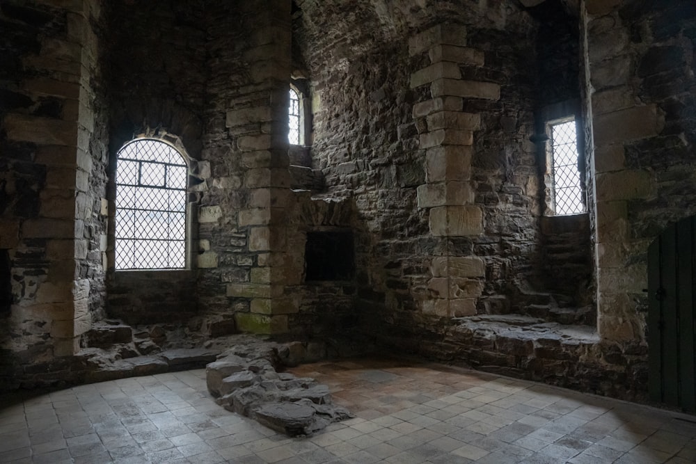 une chambre avec deux fenêtres et un sol en pierre