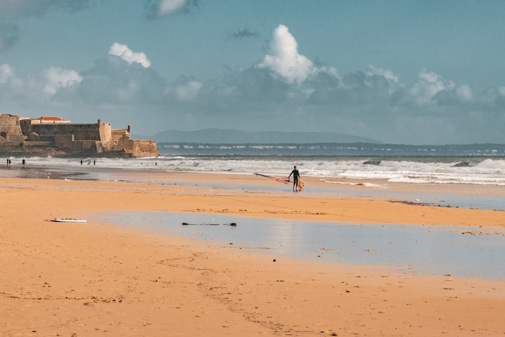 a person walking on a beach with a surfboard