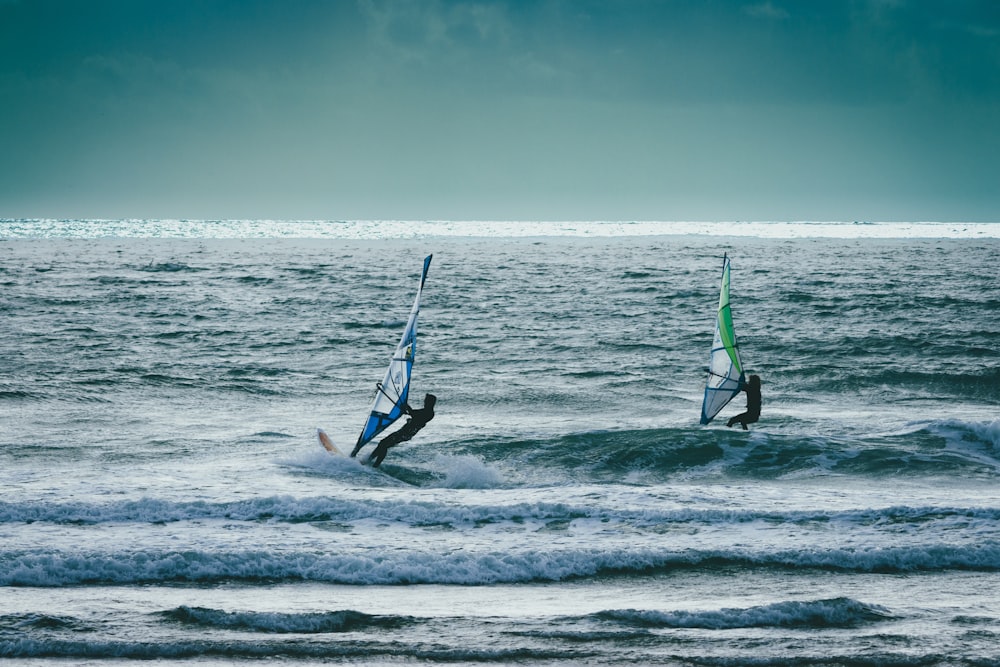 a couple of people riding surfboards on top of the ocean