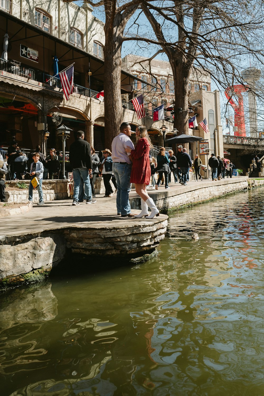 Un hombre y una mujer están de pie sobre una roca junto al agua