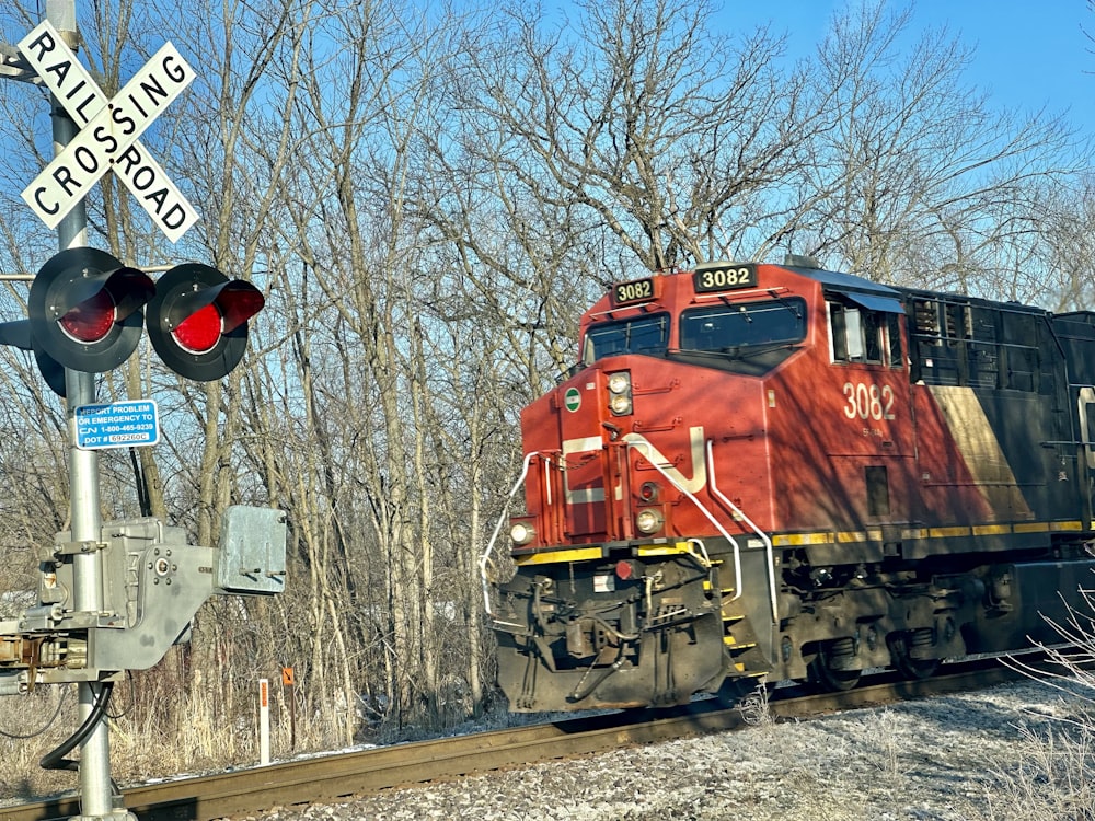 Ein roter Zug, der auf Bahngleisen neben einem Wald fährt