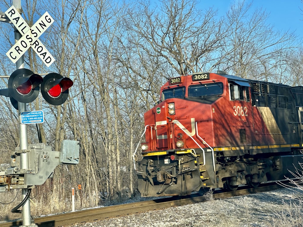 a red train traveling down train tracks next to a forest