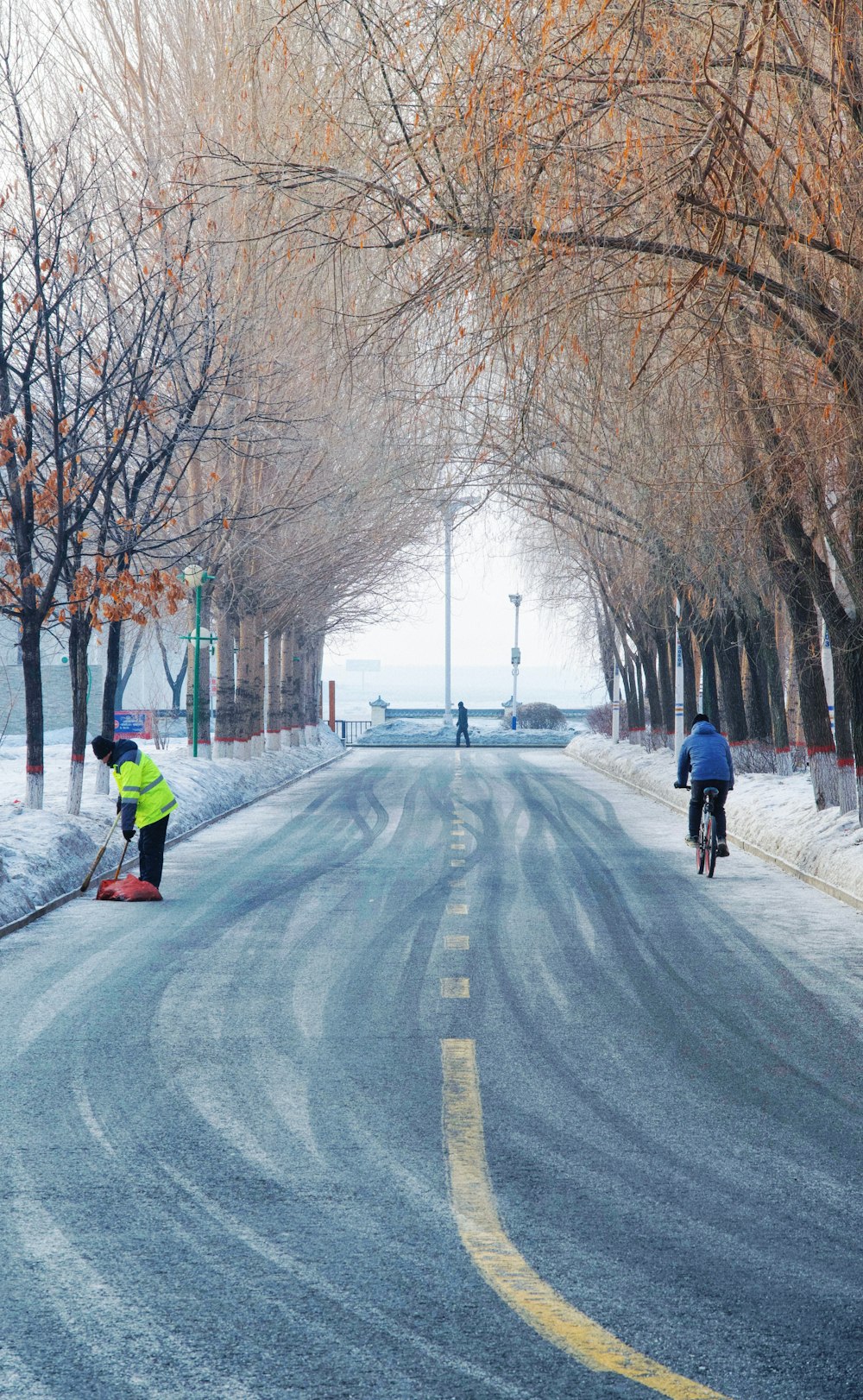 a couple of people riding bikes down a snow covered road