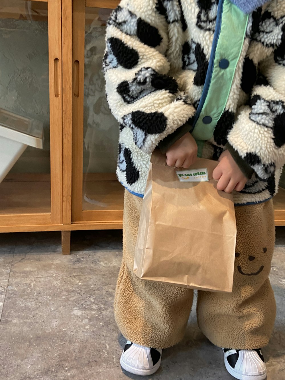 a little boy holding a brown bag in his hands