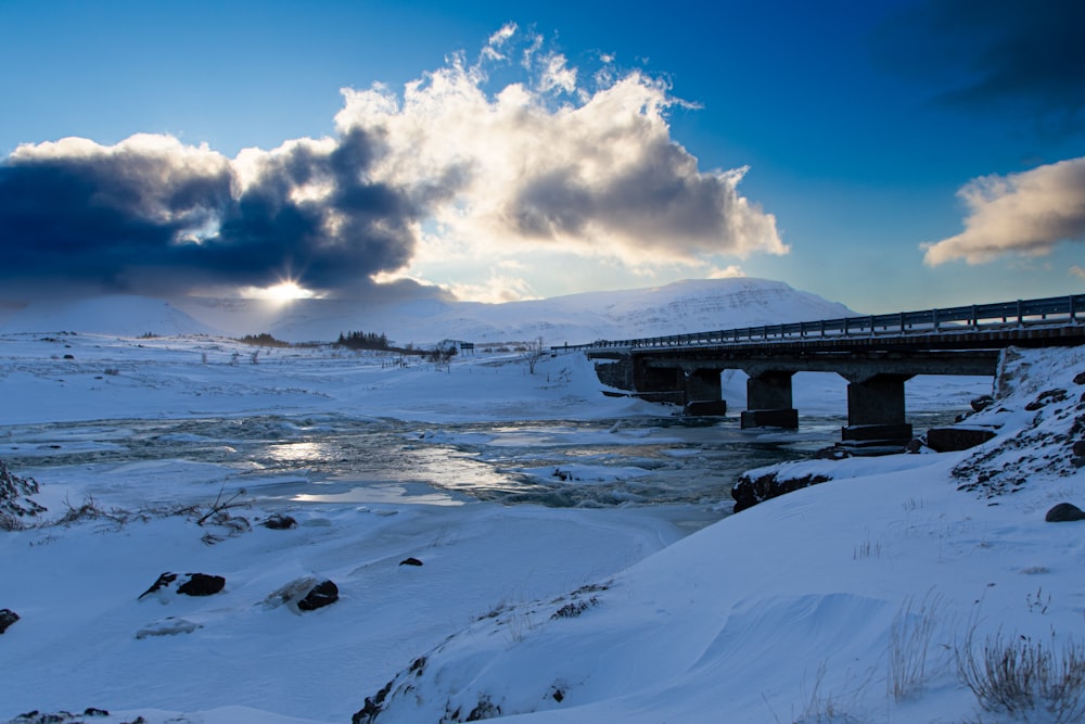 a bridge over a frozen river under a cloudy sky