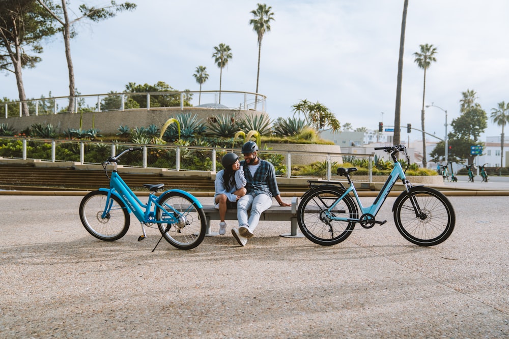 two people sitting on a bench next to two bikes