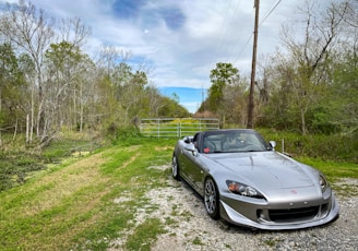 a silver sports car parked on a gravel road