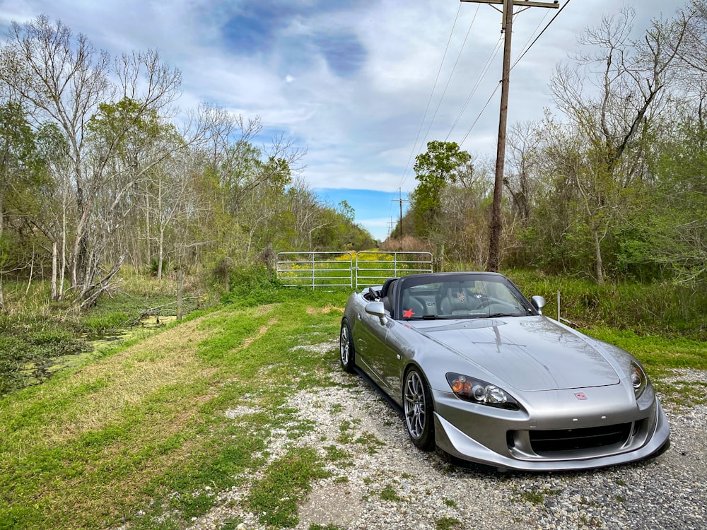 a silver sports car parked on a gravel road
