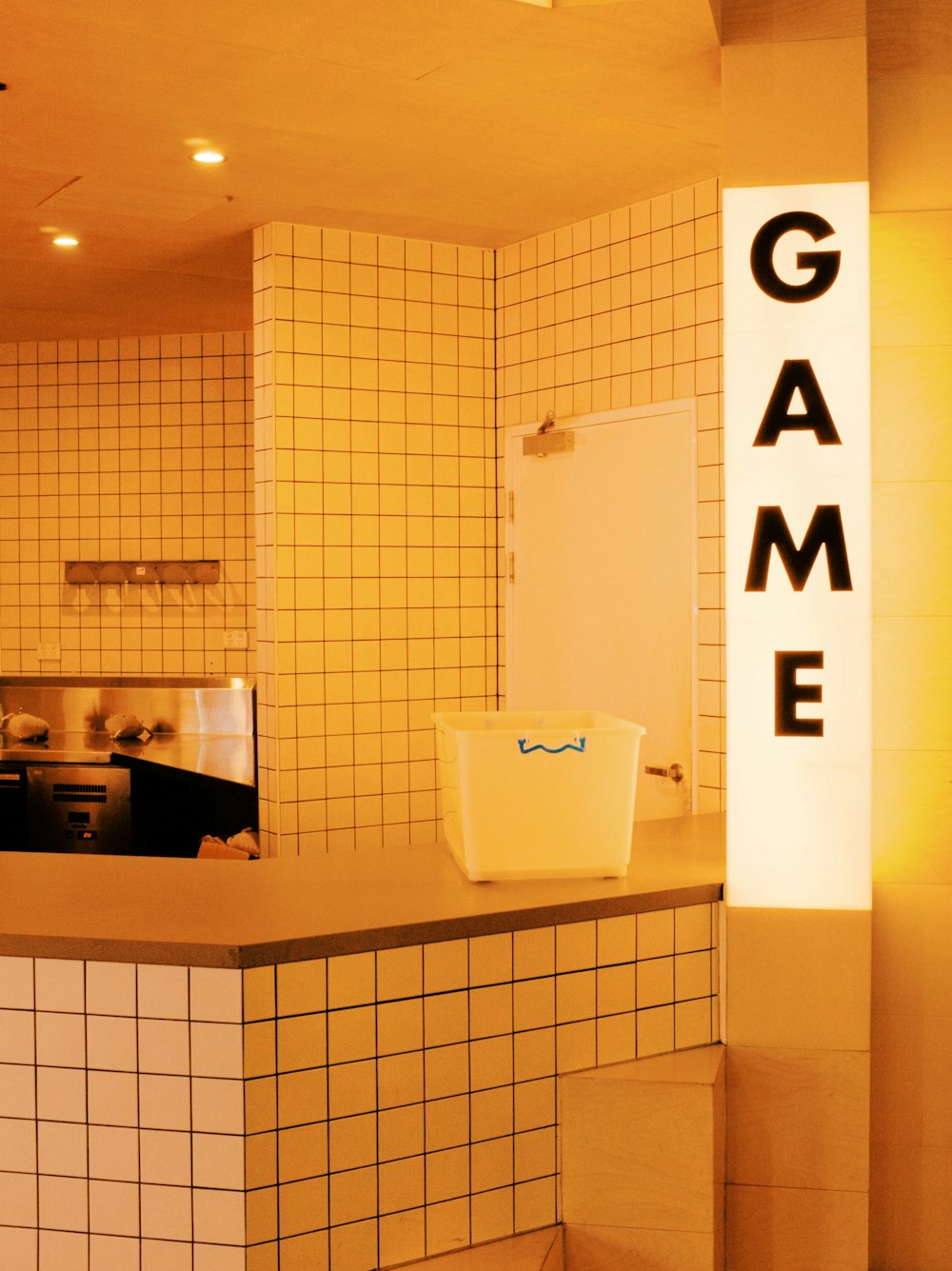a kitchen with tiled walls and a game sign on the wall