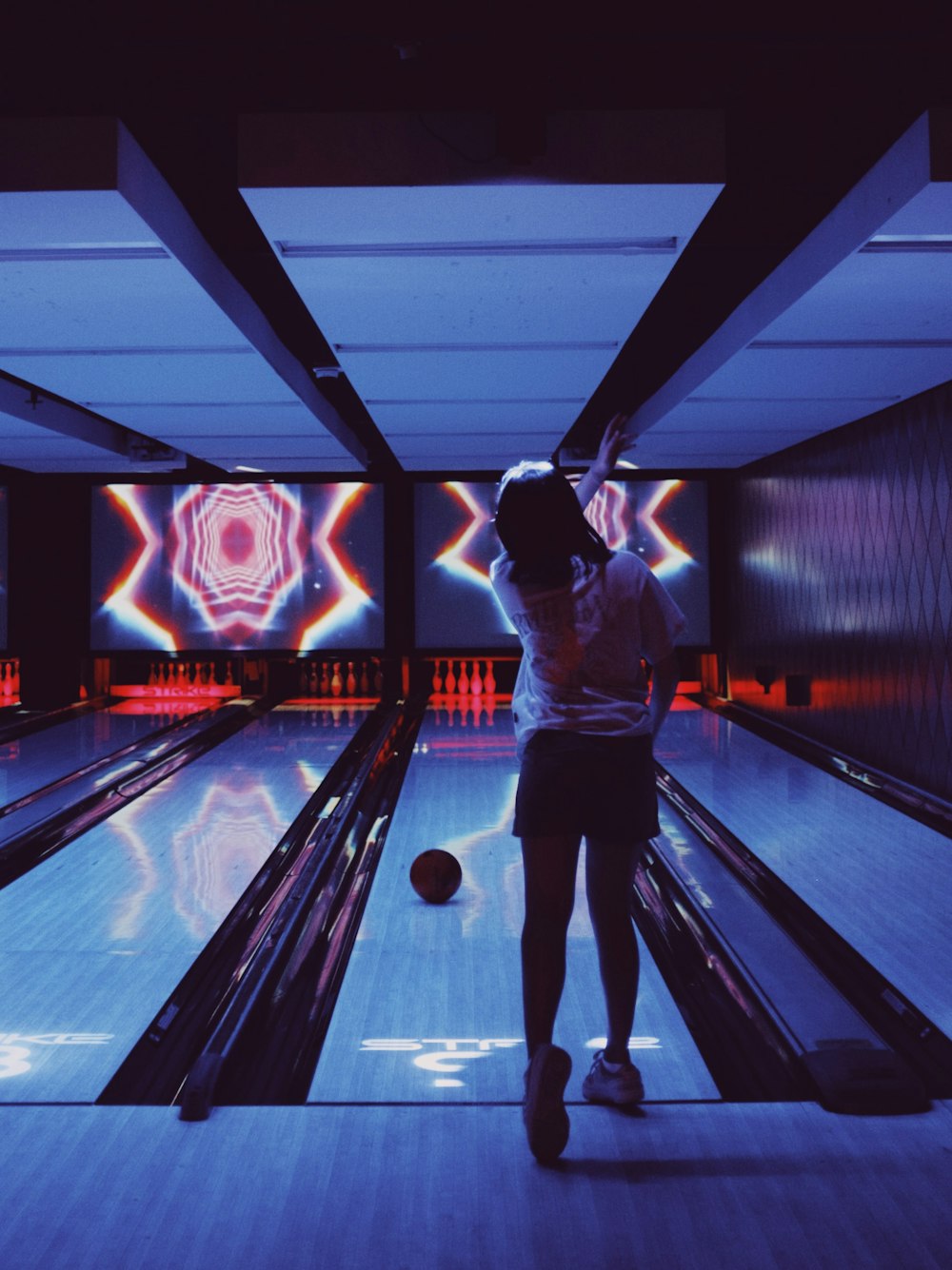 a woman is bowling down a bowling alley