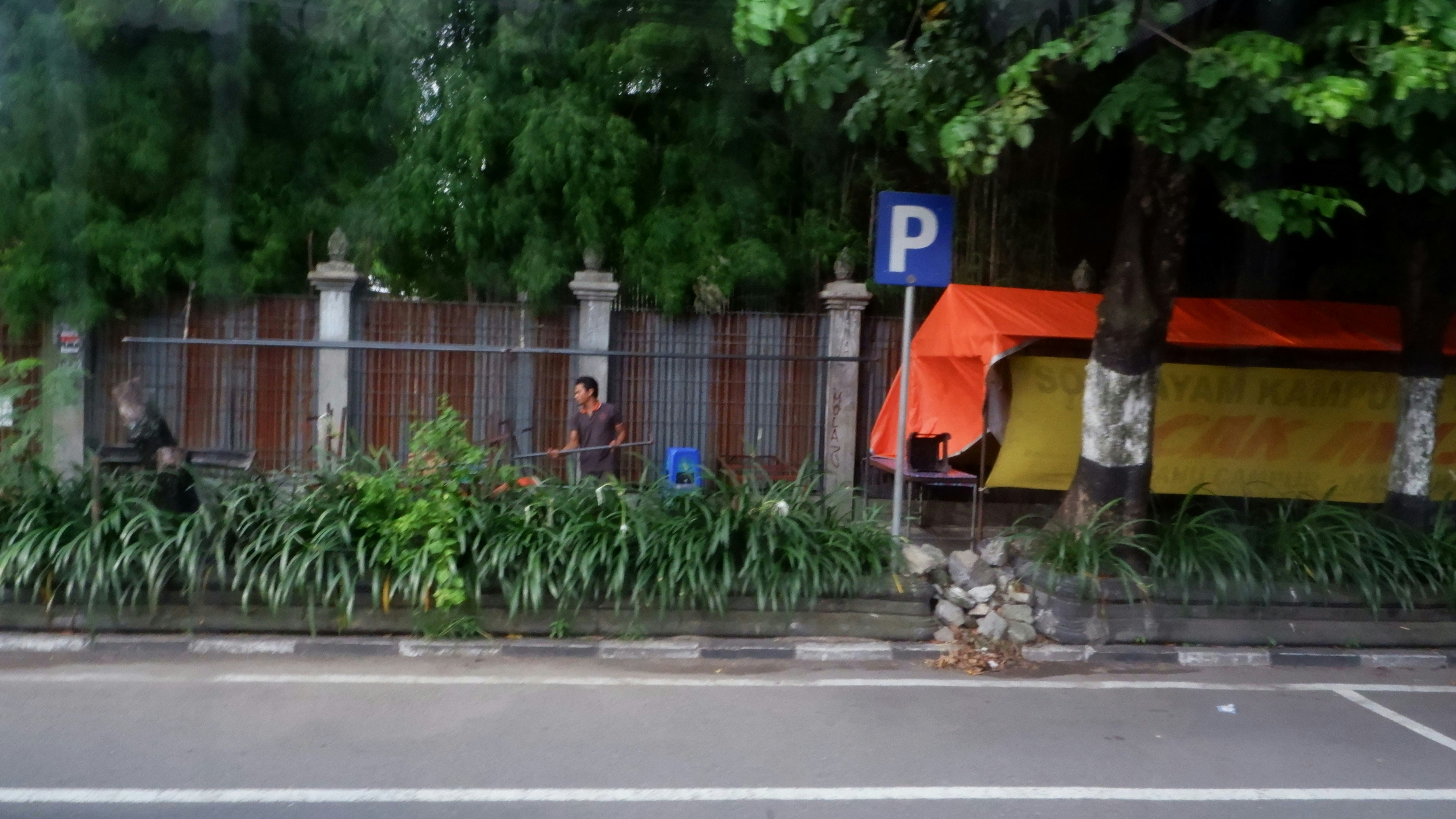 seseorang duduk di bangku di sebelah pagar