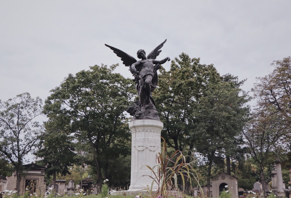 a statue of an angel on a pedestal in a cemetery
