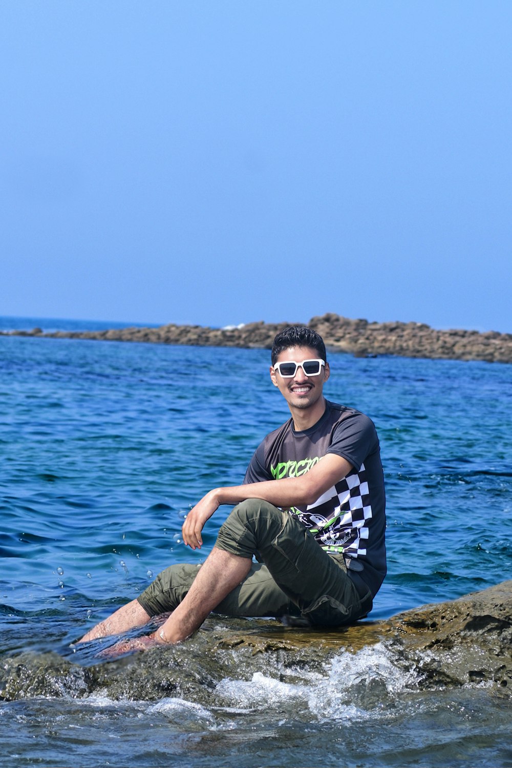 a man sitting on a rock in the water