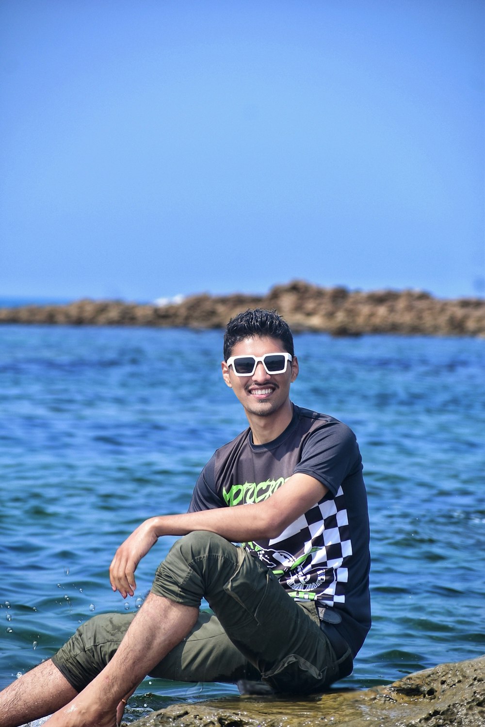 a man sitting on a rock in the water