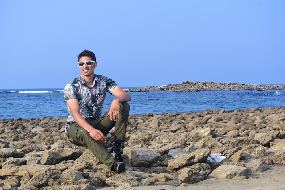 a man sitting on rocks near the ocean