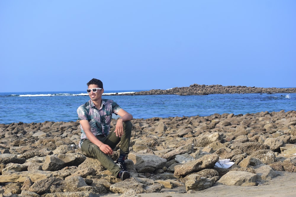 a man sitting on rocks near the ocean