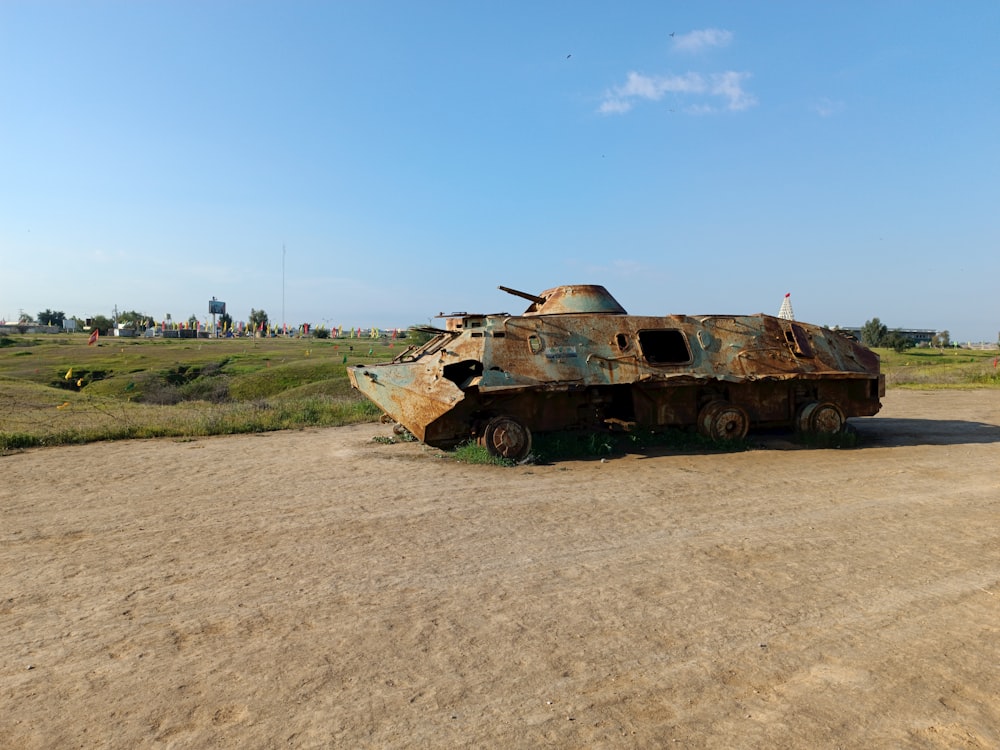 a rusted out tank sitting on top of a dirt field