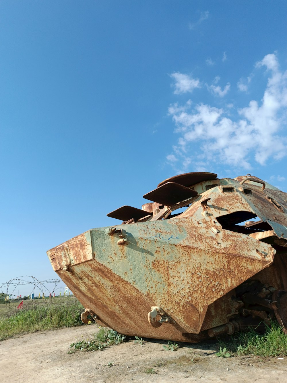 a rusted out vehicle sitting on top of a dirt field