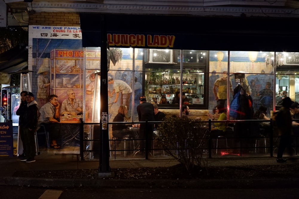 a group of people standing outside of a restaurant at night