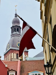a flag flying in front of a building with a clock tower
