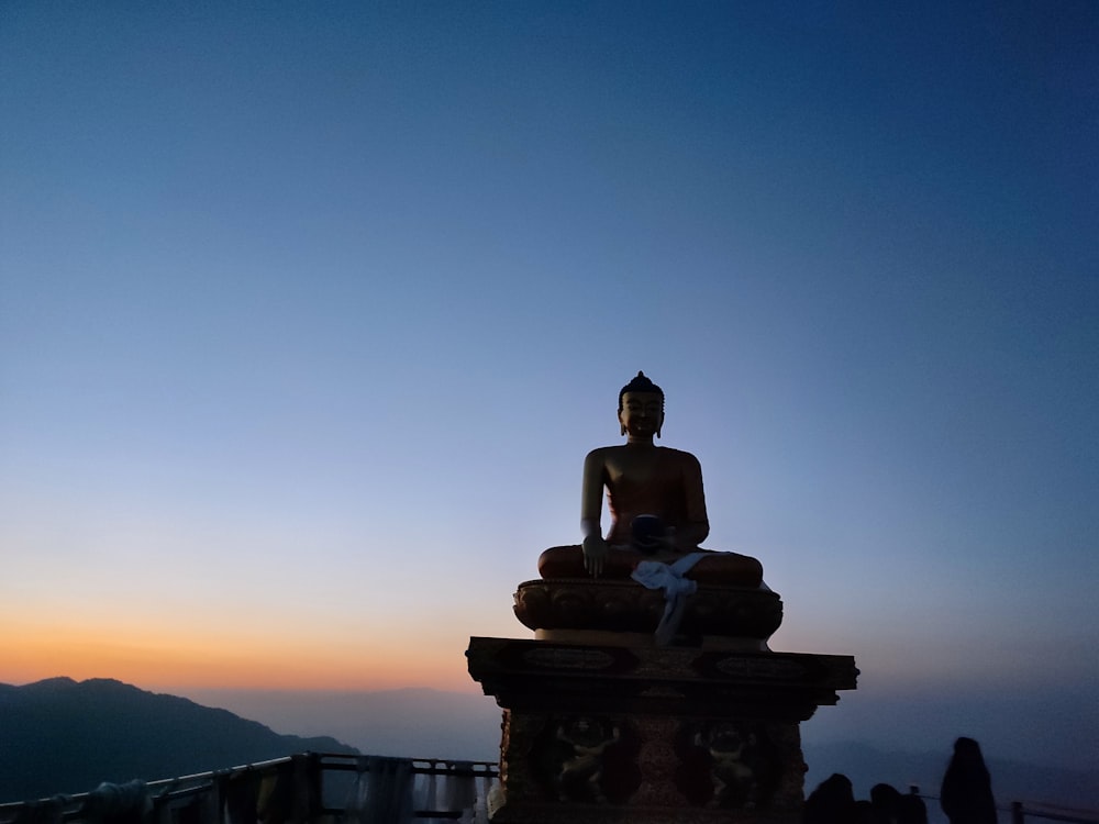 a buddha statue sitting on top of a hill