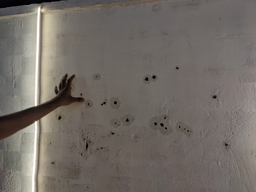 a person reaching for bullet holes in a wall