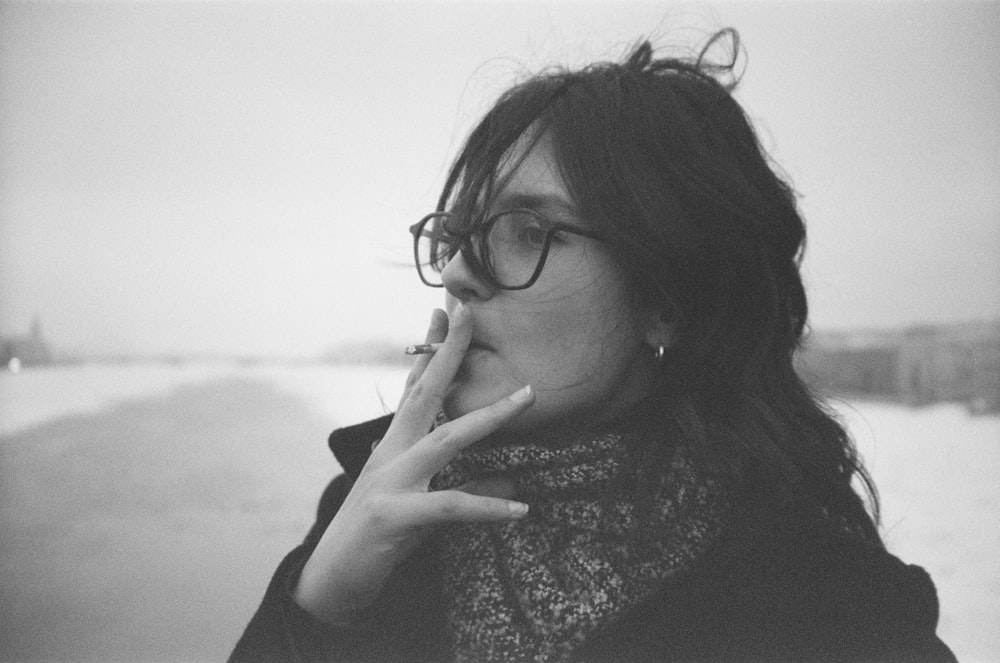a woman with glasses is smoking a cigarette