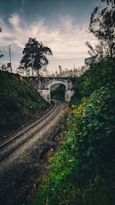 a train track going under a bridge on a cloudy day