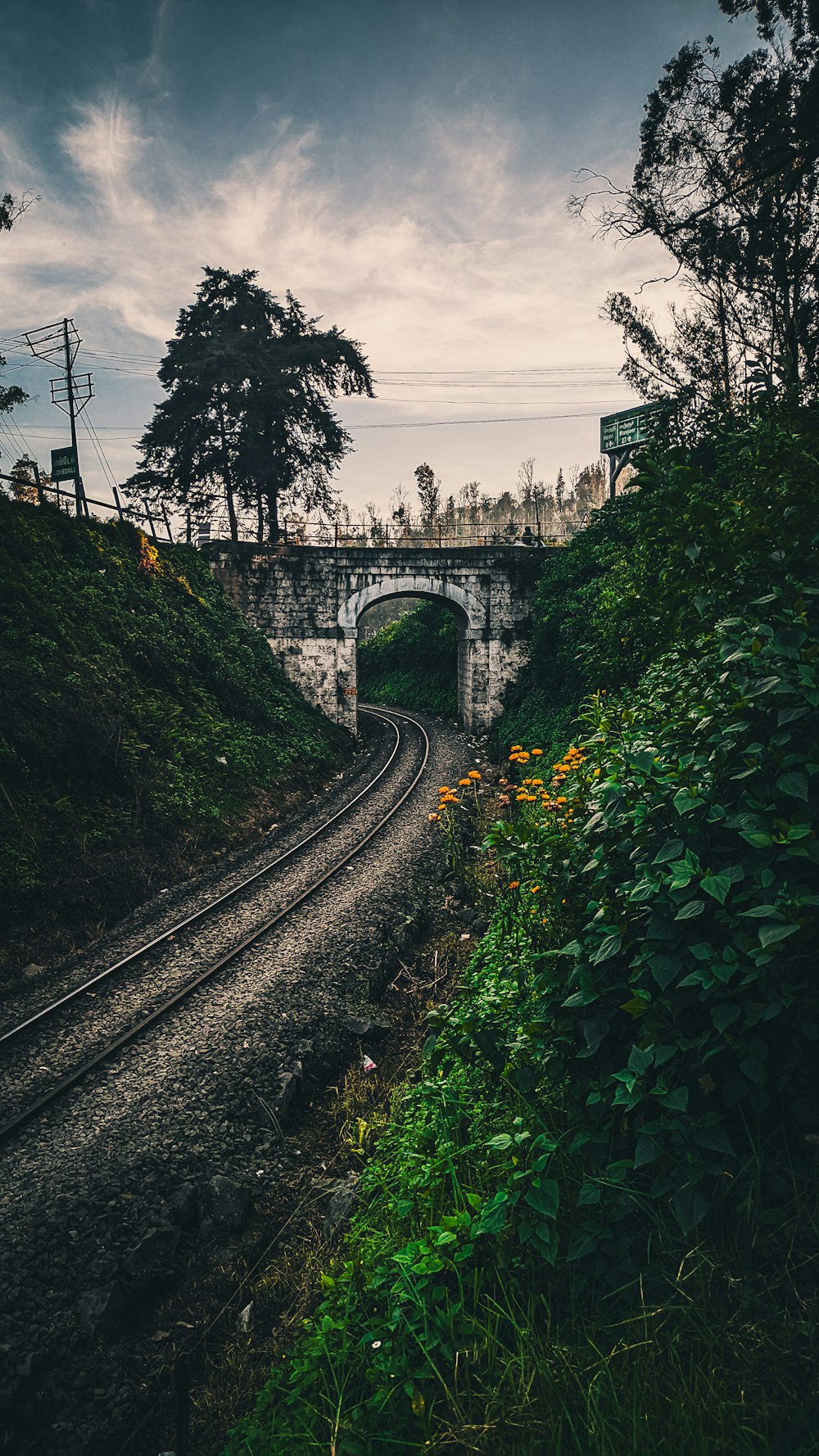 a train track going under a bridge on a cloudy day