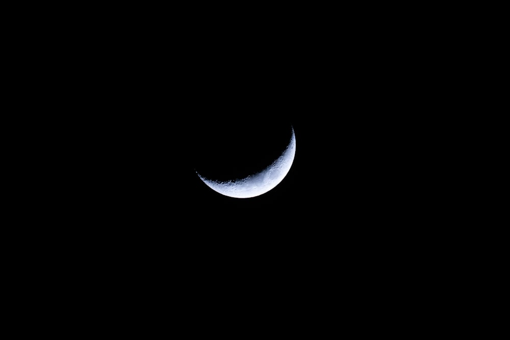 uma lua crescente é vista no céu escuro