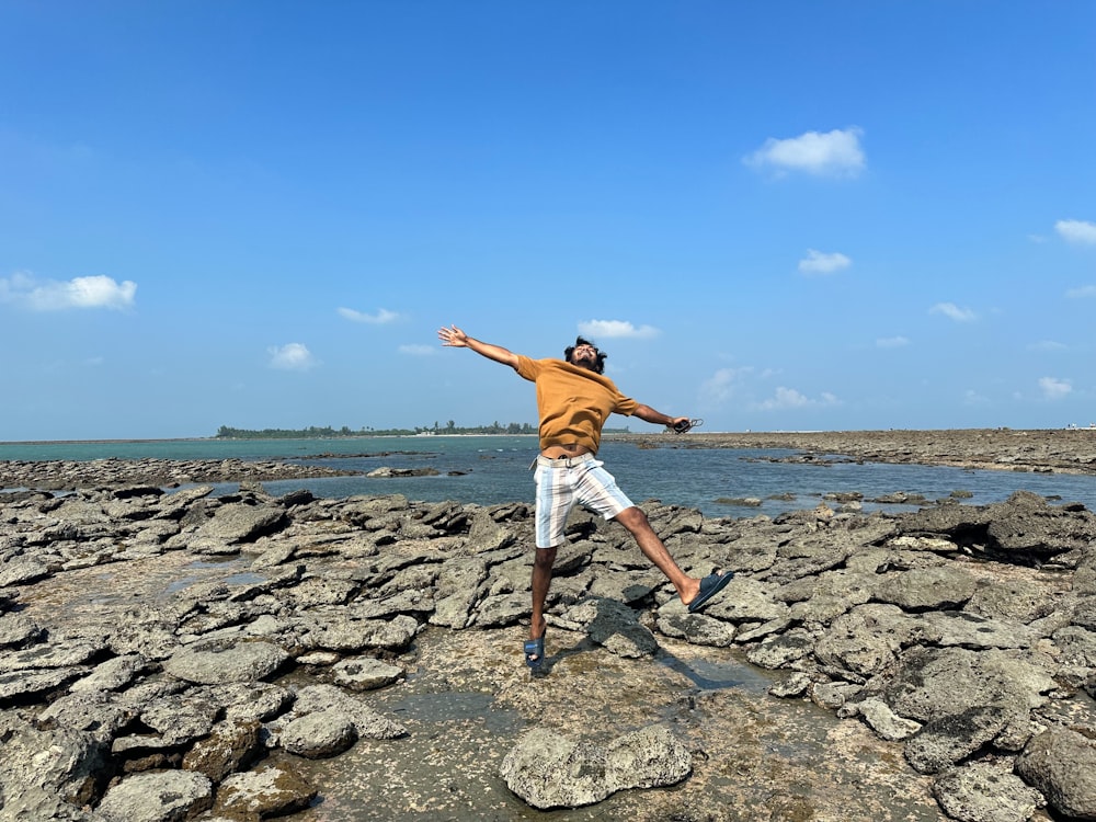 a man standing on top of a rock covered beach