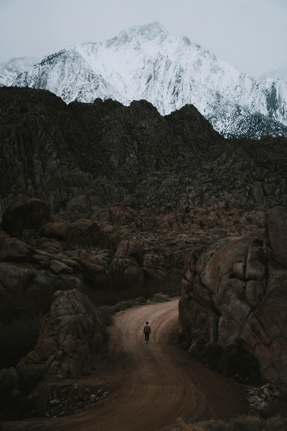 una persona caminando por un camino de tierra frente a una montaña