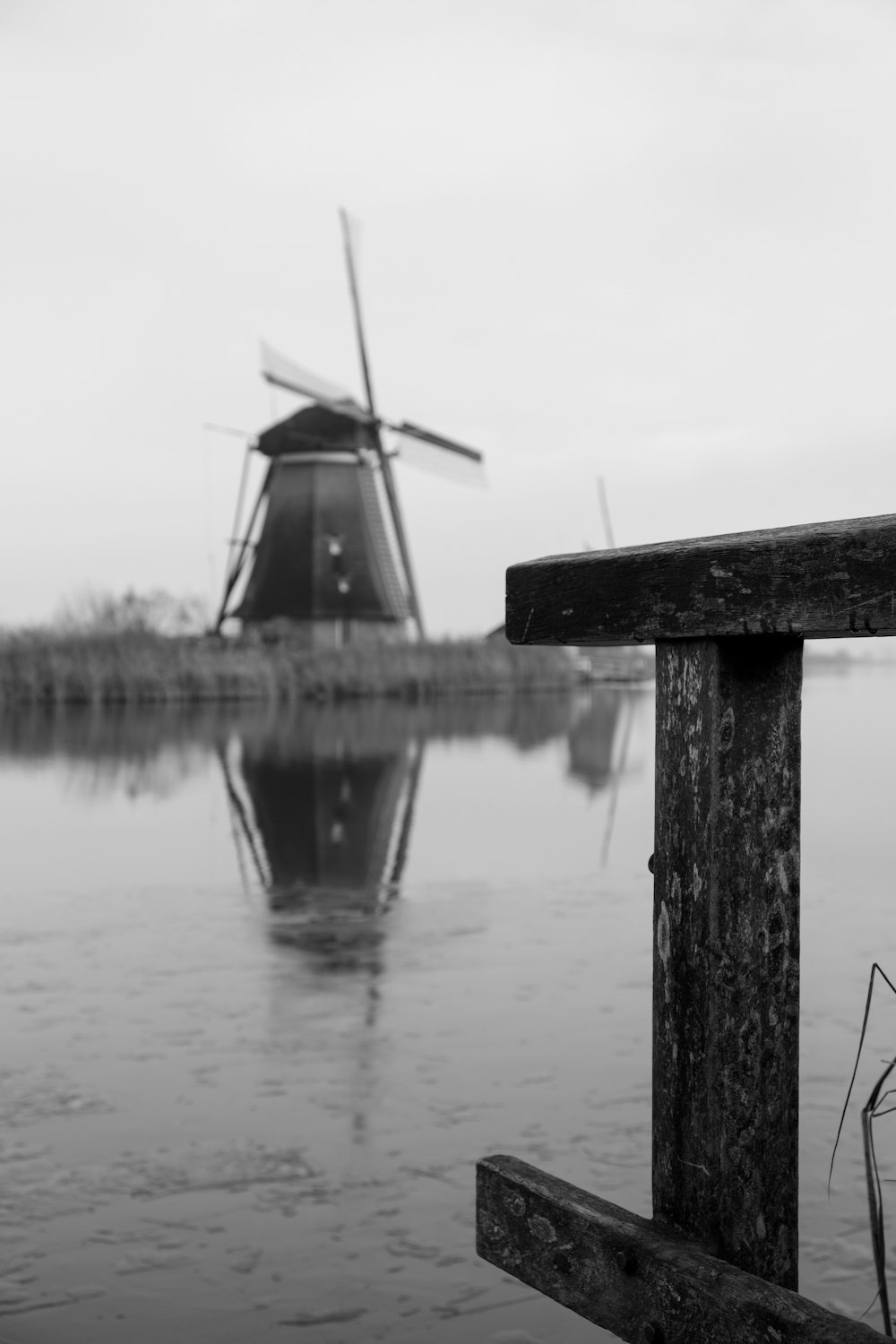 Una foto in bianco e nero di un mulino a vento nell'acqua