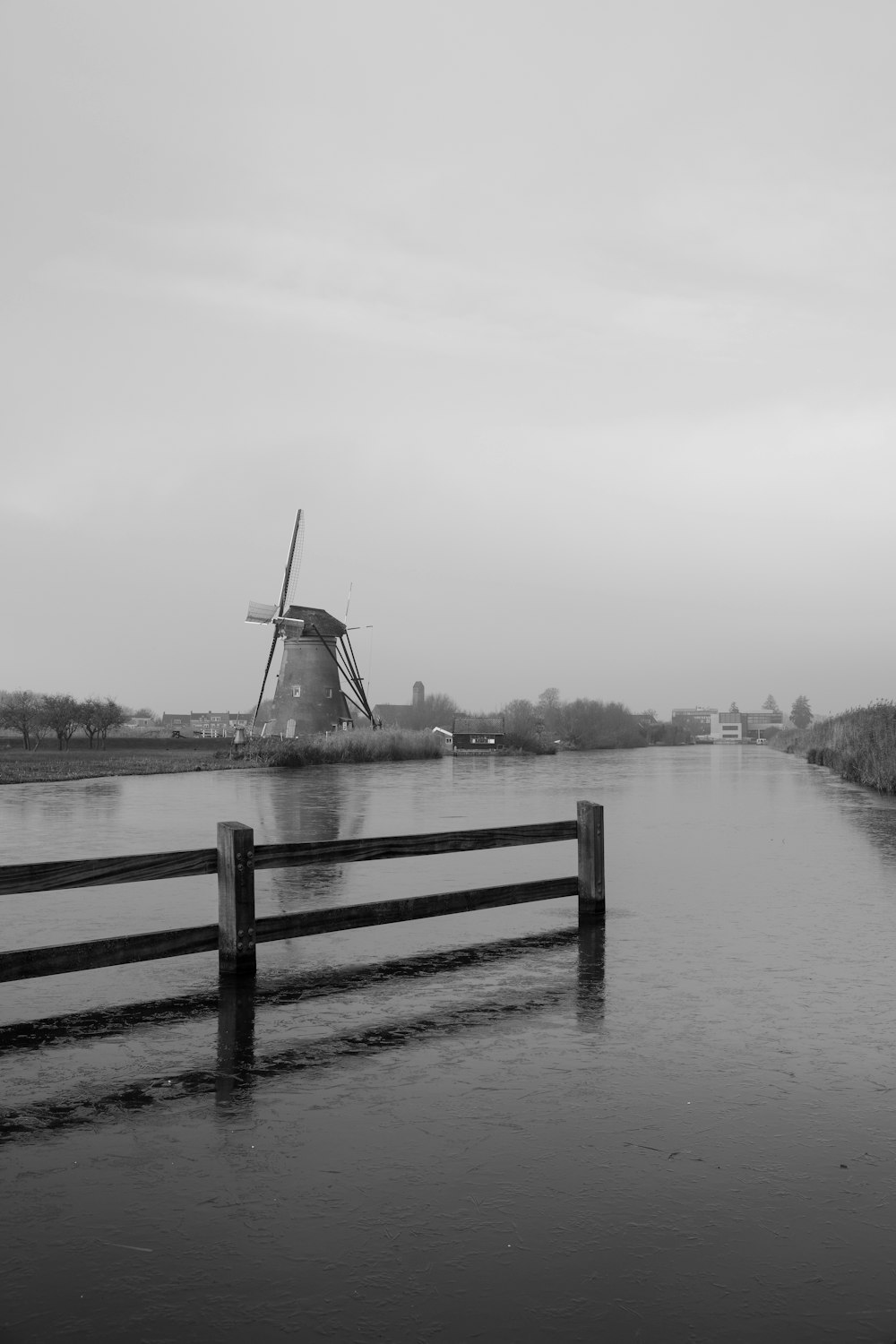Una foto in bianco e nero di un mulino a vento nell'acqua