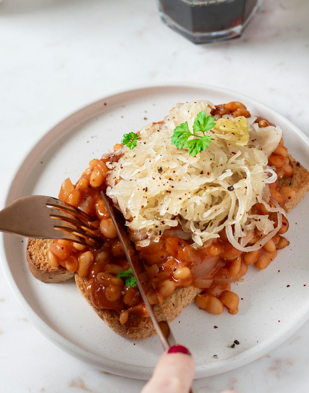 a white plate topped with a sandwich covered in beans