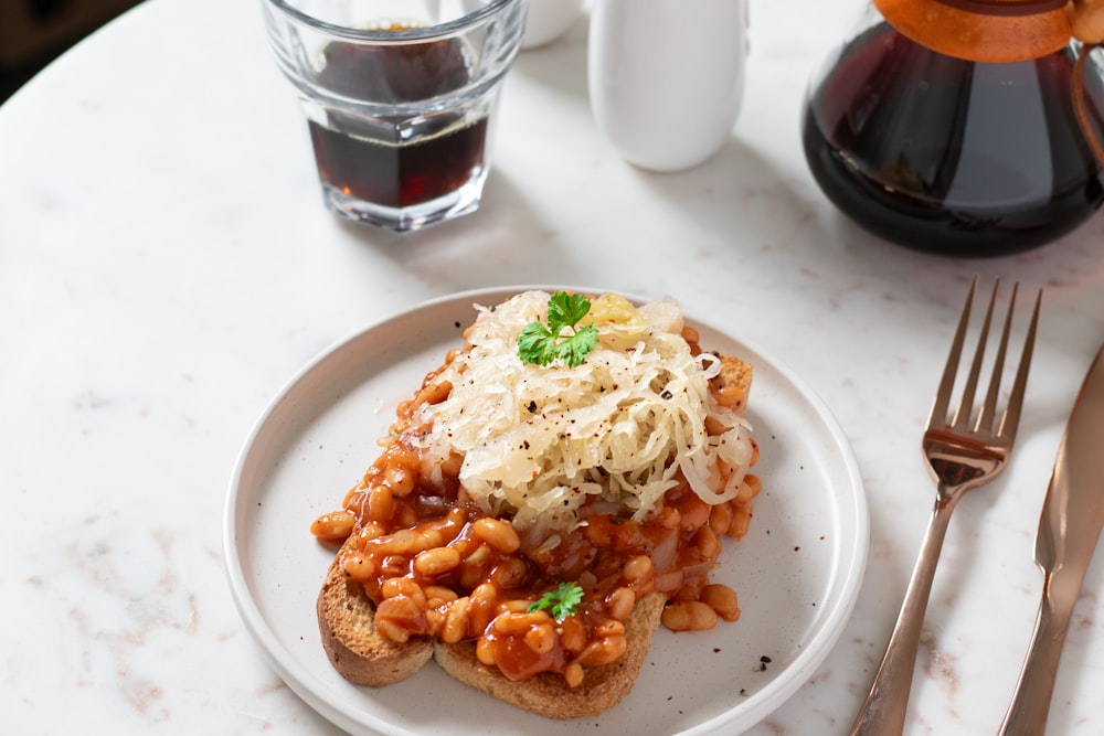 a white plate topped with a piece of toast covered in beans