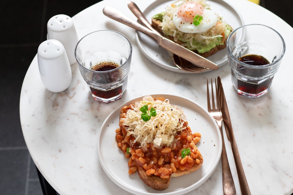 a white plate topped with food next to glasses of liquid