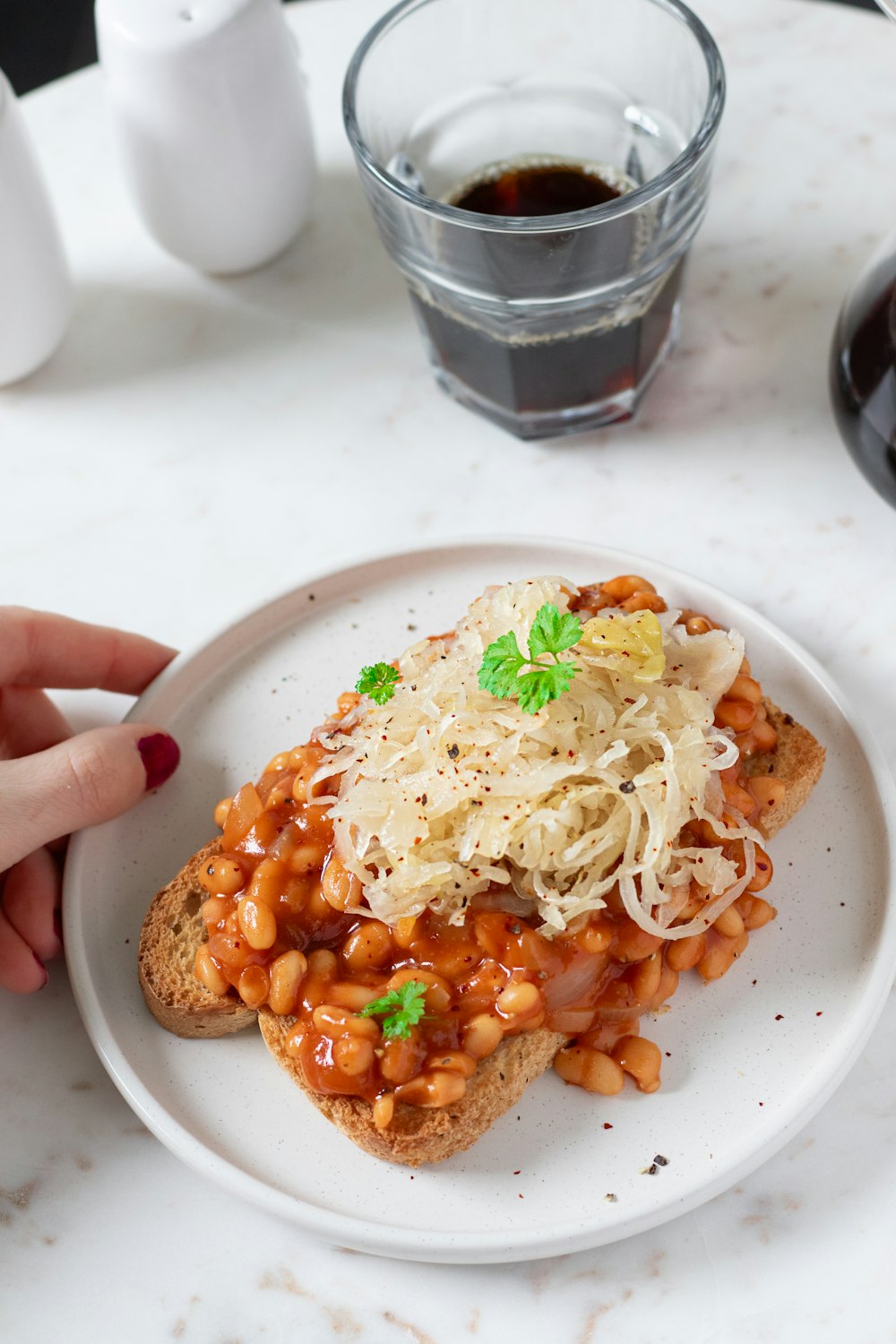 a white plate topped with a sandwich covered in beans