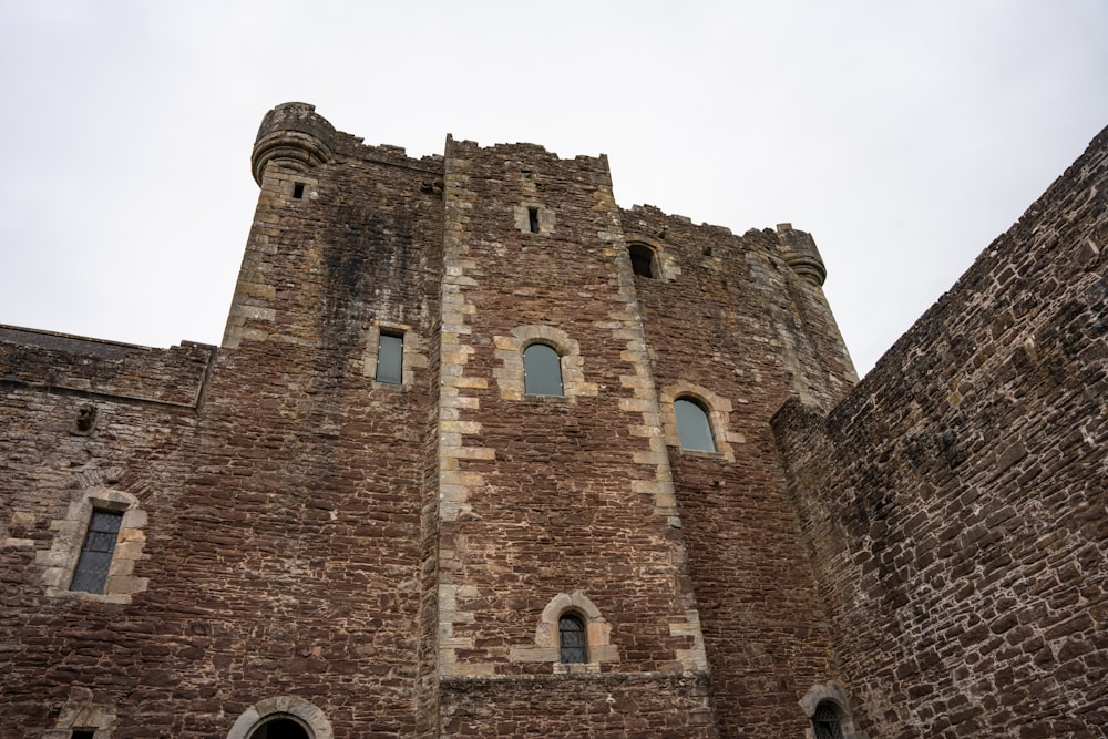 a very tall brick castle with a clock on it's side