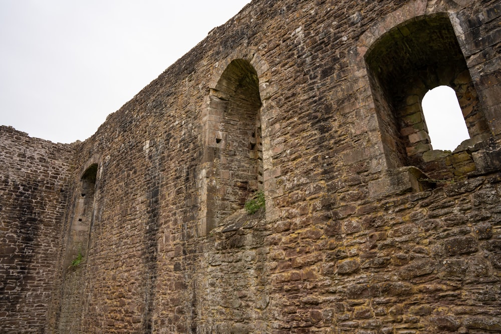 a stone wall with two windows and a bench in front of it